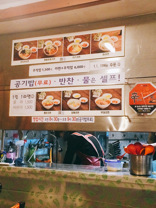 由於這裡是傳統的食店,並沒有預計會有外國人前往,因此店內是沒有中文字的,如果看不懂韓文的話,廚房門外也有貼上照片的,方便客人點餐。從上面由左至右排列的是:三淑拉麵、海鮮拉麵、芝士拉麵及蔥拉麵。而下面由左至右排列的是:辛辣拉麵、芝麻拉麵及部隊拉麵。所有拉麵都是5000KRW,如果想要吃SET的話則6000KRW,包括一個紫菜飯團。
